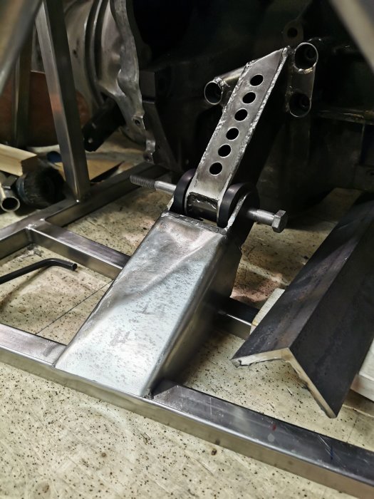 Närbild av en metallkonstruktion med en delvis monterad pedal i en bilrestaureringsverkstad.