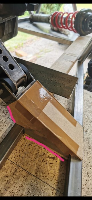 Metalldel som "boxas in" i ram med 2 mm plåt under en bils upphängningssystem.