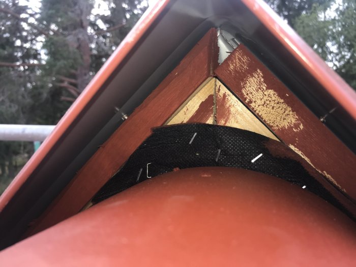 Hörndetalj på hus med synligt plåt- och träarbete samt svart väv, fråga om kvaliteten på arbetet.