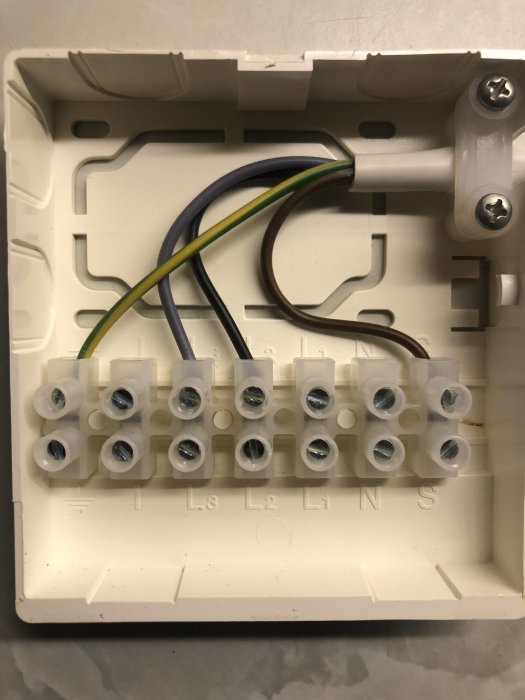 En öppen kopplingsdosa med anslutna ledningar och markerade anslutningar för L1, L2, L3, N, S.