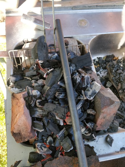 Kycklingfilé med stål inlagd på stålstång över en glödande grill med träkol.