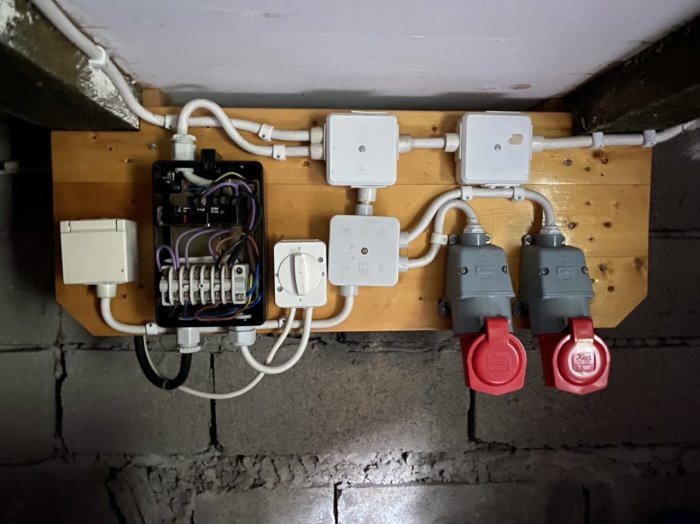 En källarvägg med elektriska installationer inklusive en säkerhetsbrytare, vägguttag och två röda 16A CEE-uttag.
