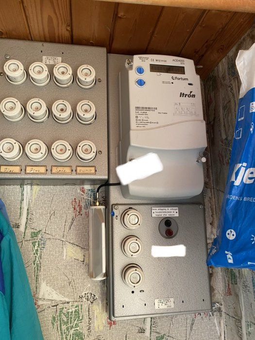 Elcentral och cee uttag i sommarstugans källare med synliga ledningar och kabelskyddsrör.