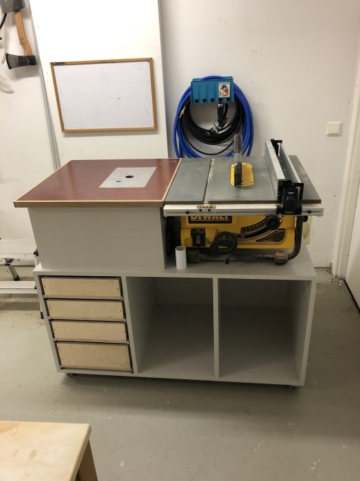 Ett nymonterat fräsbord med lådor och en bordsåg i ett verkstadsrum.