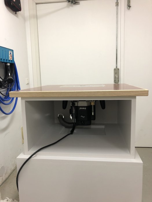 Monterat fräsbord med en överfräs installerad under bordsskivan och lediga lådfack utanför.