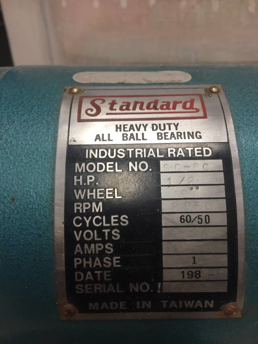 Närbild på en identifikationsskylt på en industrial slipmaskin märkt 'Standard', med tekniska specifikationer.