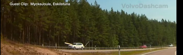 Dashcam-bild av en vit bil vid vägkant nära skog i Eskilstuna.