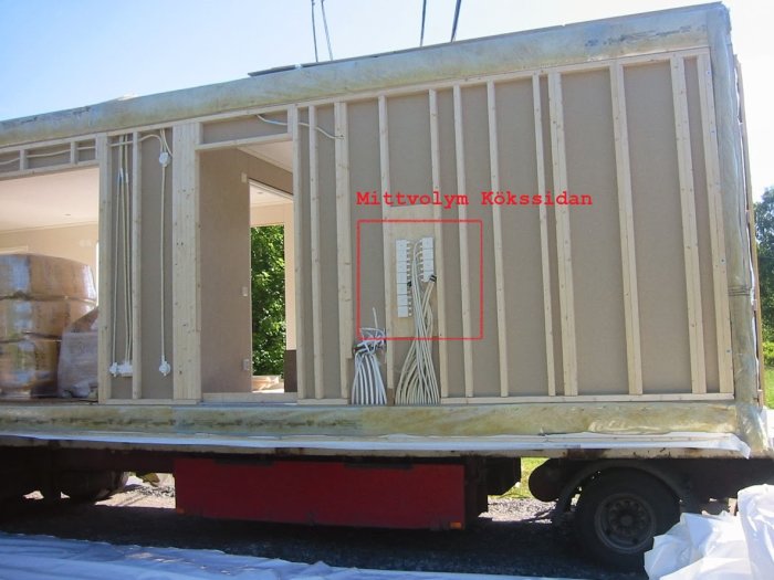 Del av ett hus under konstruktion på lastbil med öppen vägg som exponerar elektriska kopplingsdosor och kabeldragningar.