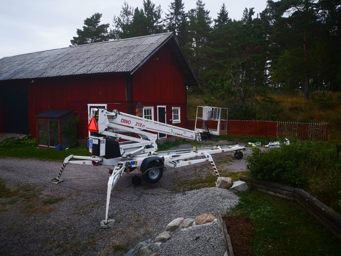 En skylift parkerad framför en röd träbyggnad med sikte på underhållsarbete.