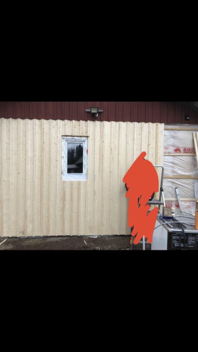 En vägg med ny träpanel där det tidigare varit två garageportar, endast ett mindre fönster kvar.