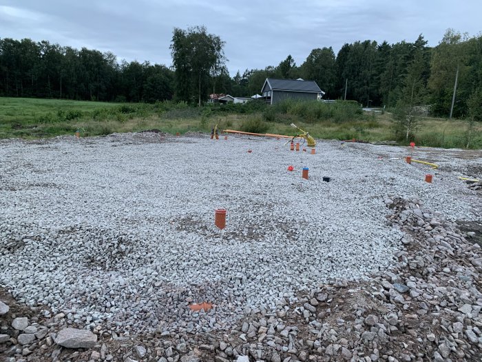 Makadamgrund med utmärkta anläggningspunkter redo för krattning och packning på byggplats.