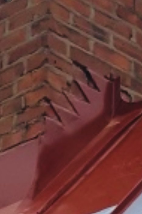 Felaktigt installerad takfot på hus med röda plåtdetaljer och tegelvägg.