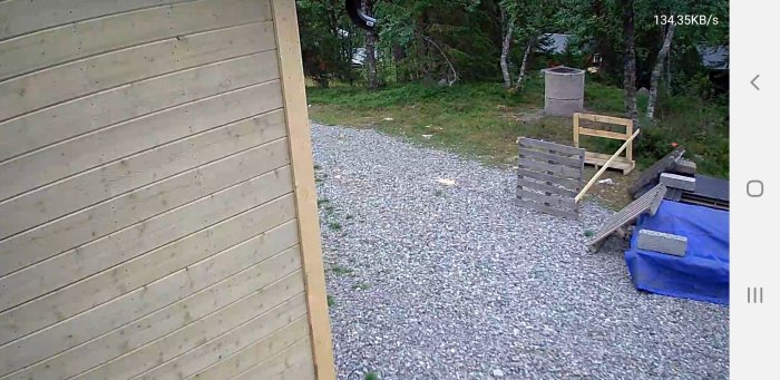 Behandlad träpanel på byggnad jämfört med obehandlad knutbräda, i en utomhusmiljö.