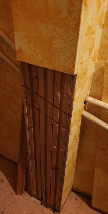 Träpelare och en överliggande balk som del av en äldre konstruktion i ett klädkammare, eventuellt icke-bärande.