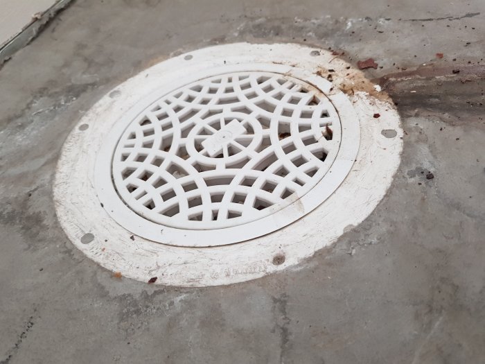 Golvbrunn i nivå med betonggolv i garage väntar på installation av klinkers.