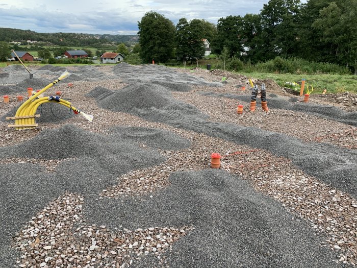 En pågående markarbetesprocess med högar av grus och flis utspridda vid en byggarbetsplats.