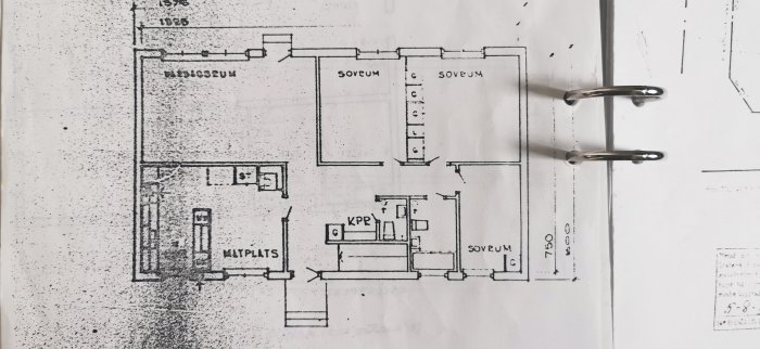 Ritning av husplanlösning som visar kök, matplats och sovrum separerade av väggar, i svartvitt.