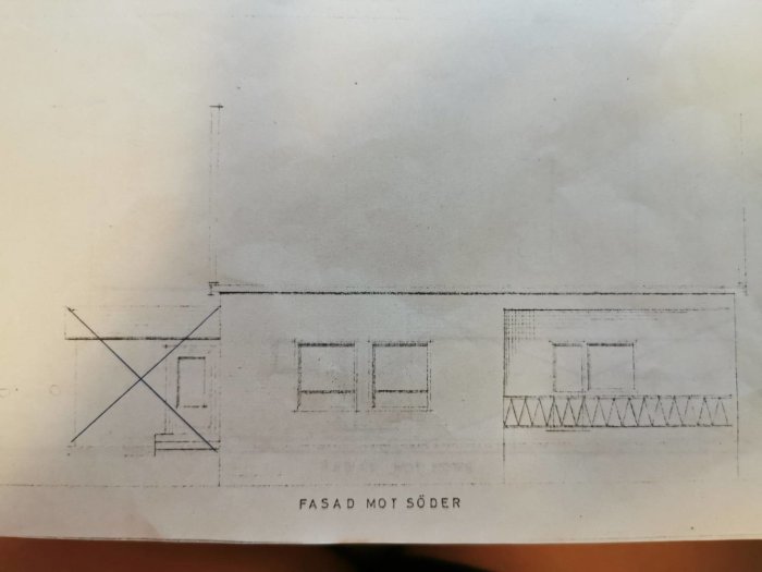 Gammal planritning av husfasad med osäker vägg indikerad med bortsuddningar och överkryssningar.