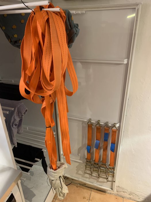 Orange spännband hängande på en torkställning med handduk vid metalldelar för att skydda under tvätt.