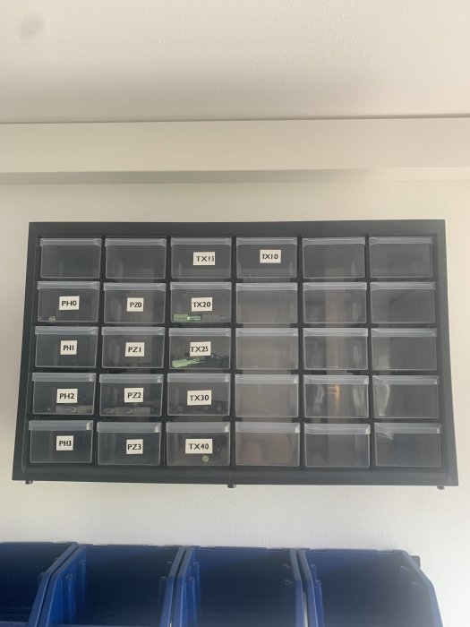 Väggmonterad förvaringshylla med uppmärkta fack för olika skruvbitsstorlekar.