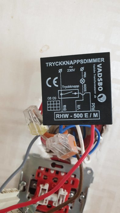 Tryckknappsdimmer med schematisk märkning kopplad med blå, röd och vit sladd till elinstallation.