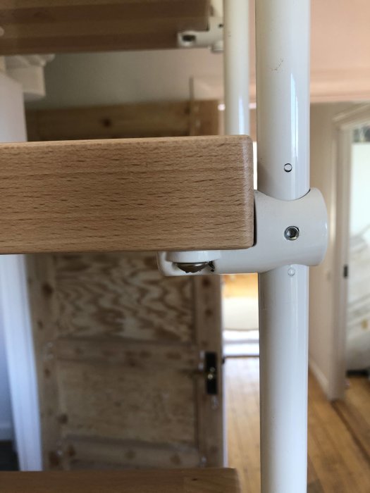 Nyligen reparerad möbeldel med träplugg och trälim, visar fastskruvad träbit på vit pelare med korrekt placerade skruvhål.