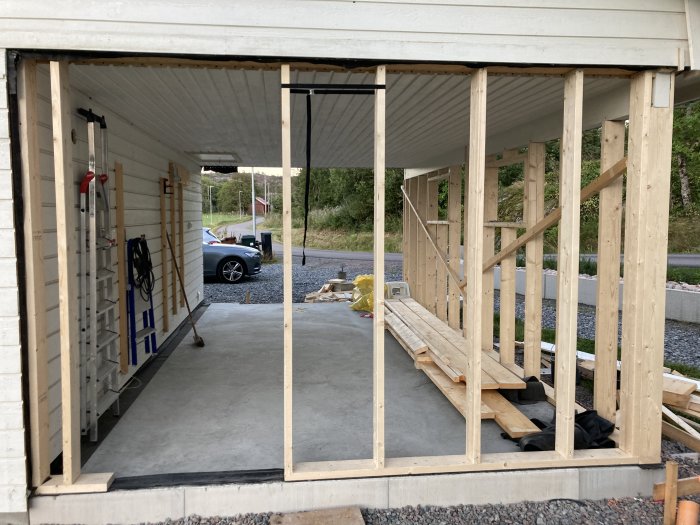 En nybyggd trästomme utan stöttor i ett byggprojekt med en bil i bakgrunden.