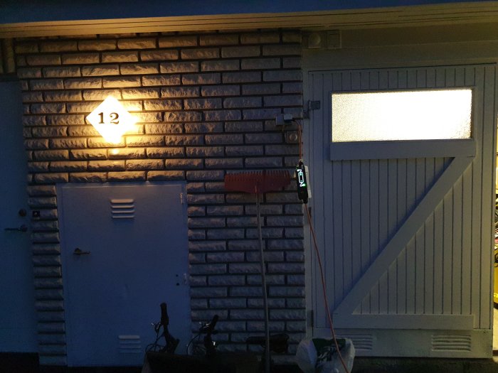 En laddbox monterad på en tegelfasad vägg bredvid ett garageport, med en sladd som hänger fritt.