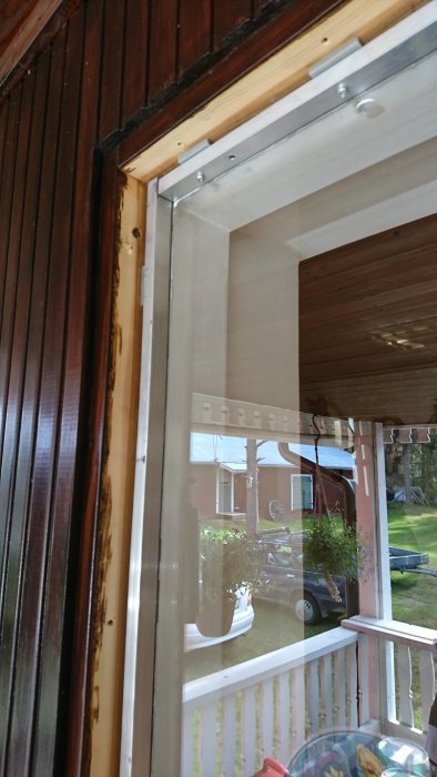 Dåligt isolerat sidofönster vid dörren med synlig aluram och tunn räfflad ruta.