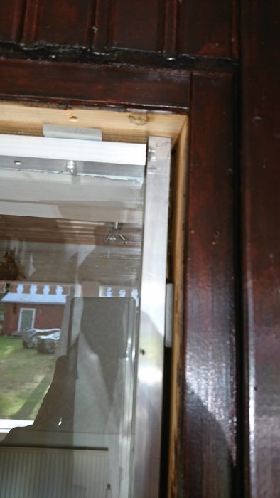 Öppnat sidofönster utan isolering, med en 3mm tjock ruta limmad mot träregeln och aluram utanför ett hus.