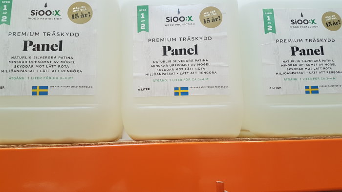 Dunkar med träskyddsmedel Sioo:X för paneler, etiketter med produktinformation.