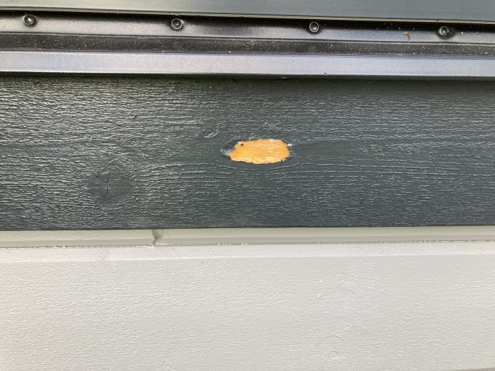 Vägg med färgbubbla på svartmålad plåt under svart list och över vit kant.