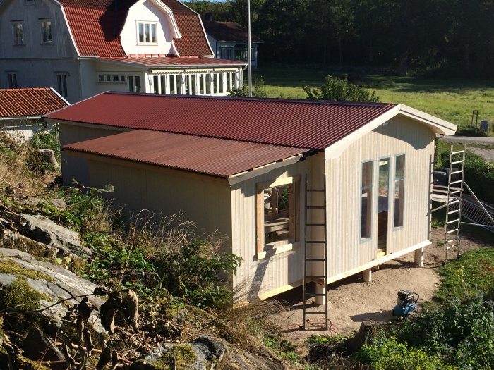 Nybyggt hus med två takdelar i behov av avvattningssystem, fotograferat nära en bergskant.