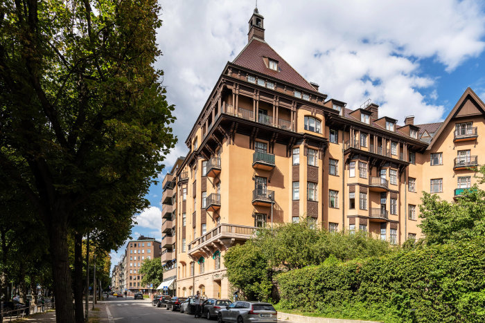 Ståtlig byggnad vid Narvavägen i Stockholm med flera balkonger och grönska.