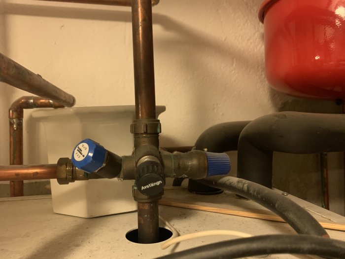 VVS-installation med kopparledningar, avstängningsventiler och isolerade rör under en bänk.