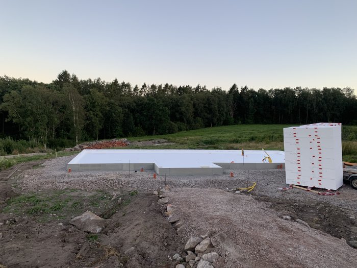 Förberedelse av husgrund med frigolitisolering och markarbeten omgiven av skog.