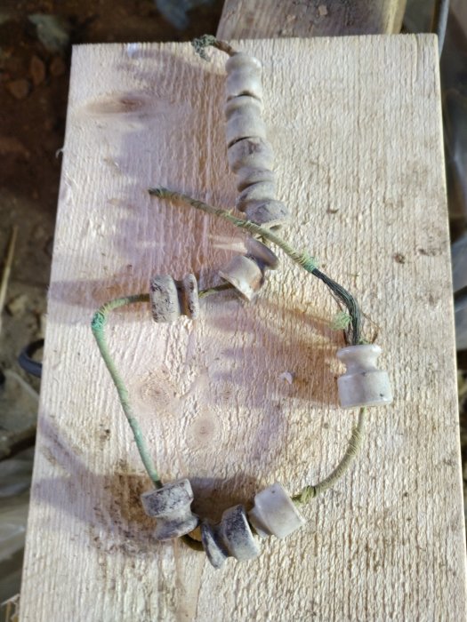 Gamla keramiska isolatorer monterade på en träplanka, tänkta för att användas vid elinstallation.