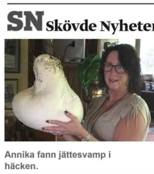 Kvinna håller en stor vit svamp, artikelrubrik från Skövde Nyheter i bakgrunden.