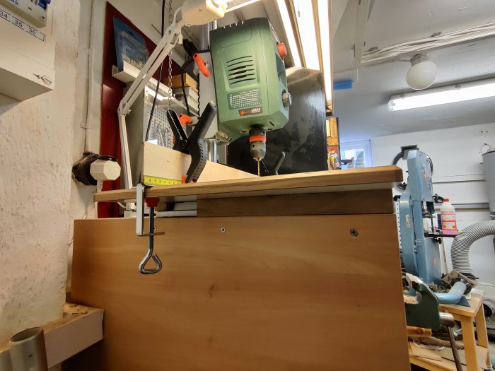 Ett hemmagjort, justerbart arbetsbord för en pelarborr, gjort av en laminerad kökslucka, med en vinkelprofil och tvingar.
