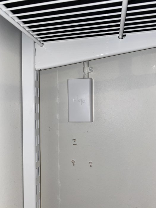 Plejd enhet installerad på vägg under vit ventilationsränna, för smartare styrning av ytterbelysning.