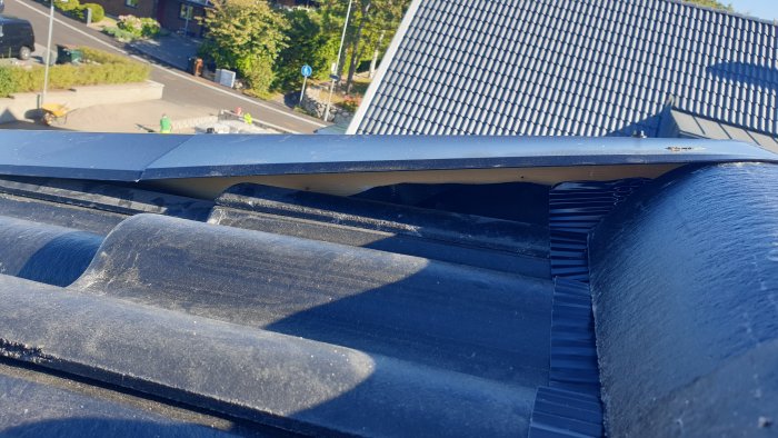 Takdetalj vid nocken med vindskiveplåten som rider över en nockpanna, skapar gap till underliggande pannor, med synliga brister i utförande.