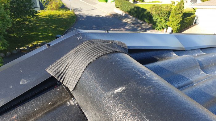 Tak med vindskiveplåt som rider över nockpanna med synligt mellanrum och uppdragen papp mot vindskivan.