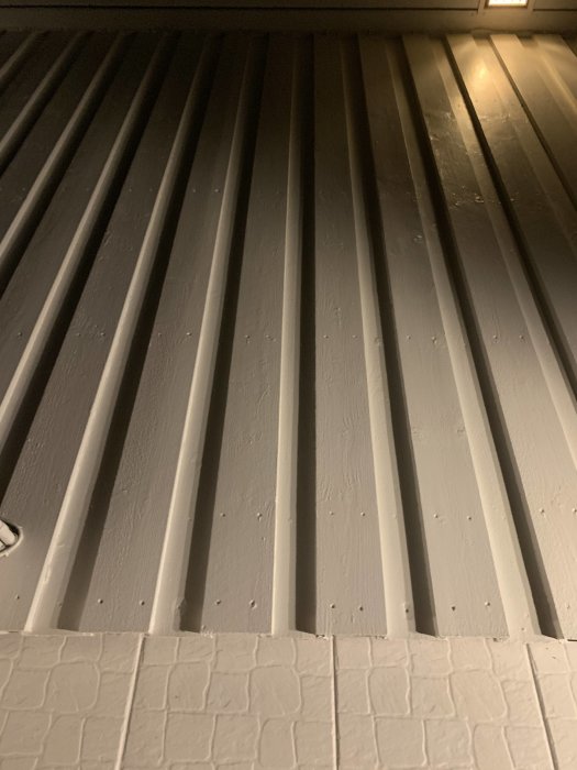 Vertikala fasadplank på ett hus vid konstgjord belysning.