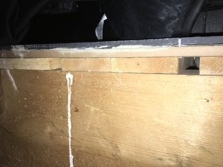 Närbild av golvgips och spånskiva i ett byggprojekt, med synliga skruvförband.