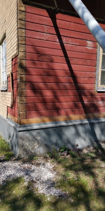 Delvis avtäckt träfasad på ett hus som visar de bakomliggande bärande stolparna, med tecken på röta vid basen.