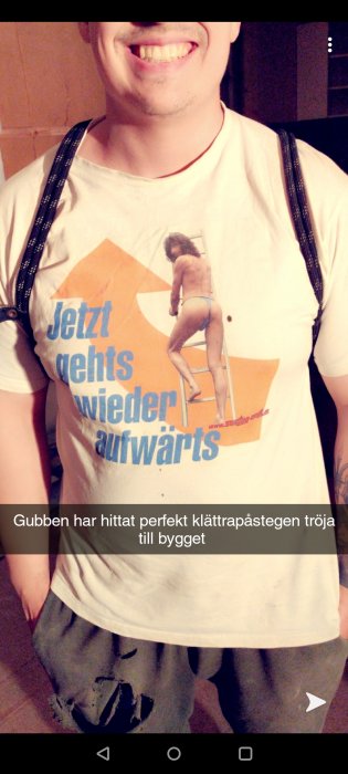 Man i t-shirt med tryck som ser ut som kvinna på stege, humoristisk byggrelaterad design.