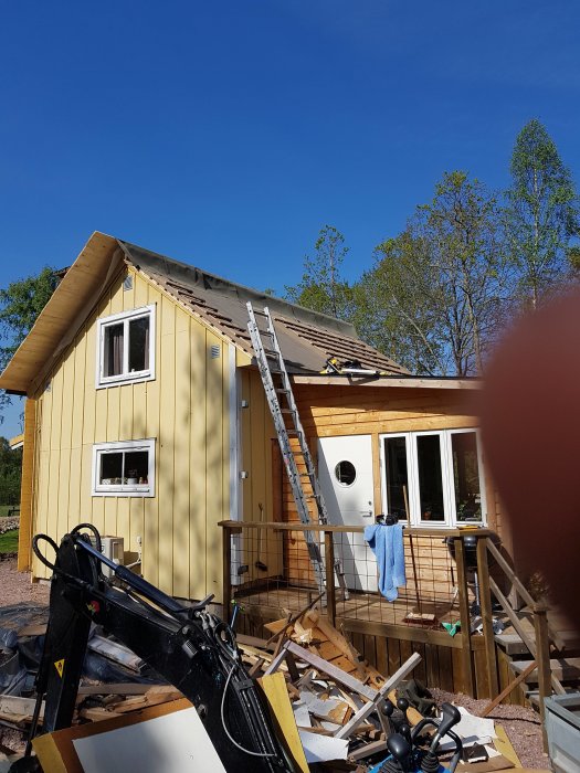 Renovering av gammal sommarstuga från 1958 med byggmaterial runtomkring och en stege mot huset.