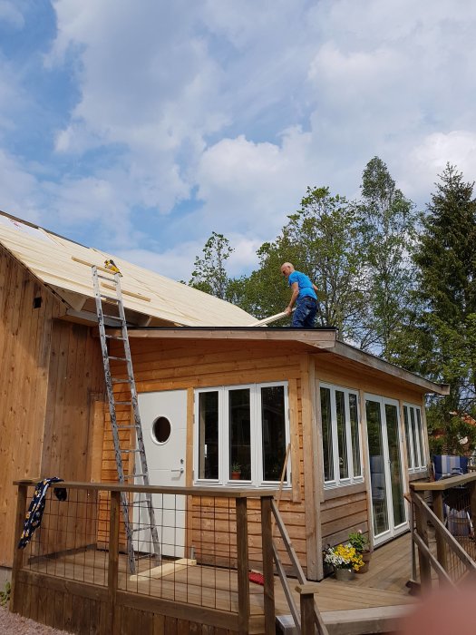 En person som arbetar på taket till en gammal sommarstuga under utbyggnad.