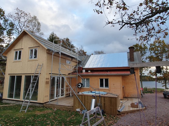 Hus under renovering med dubbelfalsad zinkad plåt på taket och byggställning vid sidan.