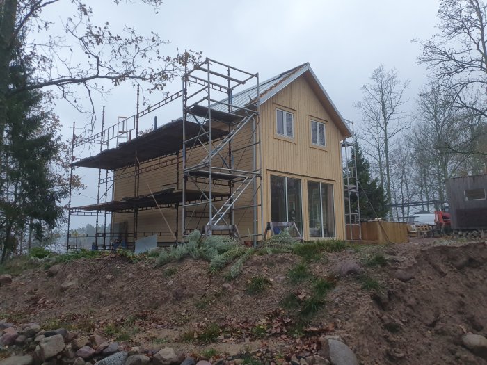 Hus under renovering med dubbelfalsad zinkplåt på taket och byggnadsställningar runtomkring.